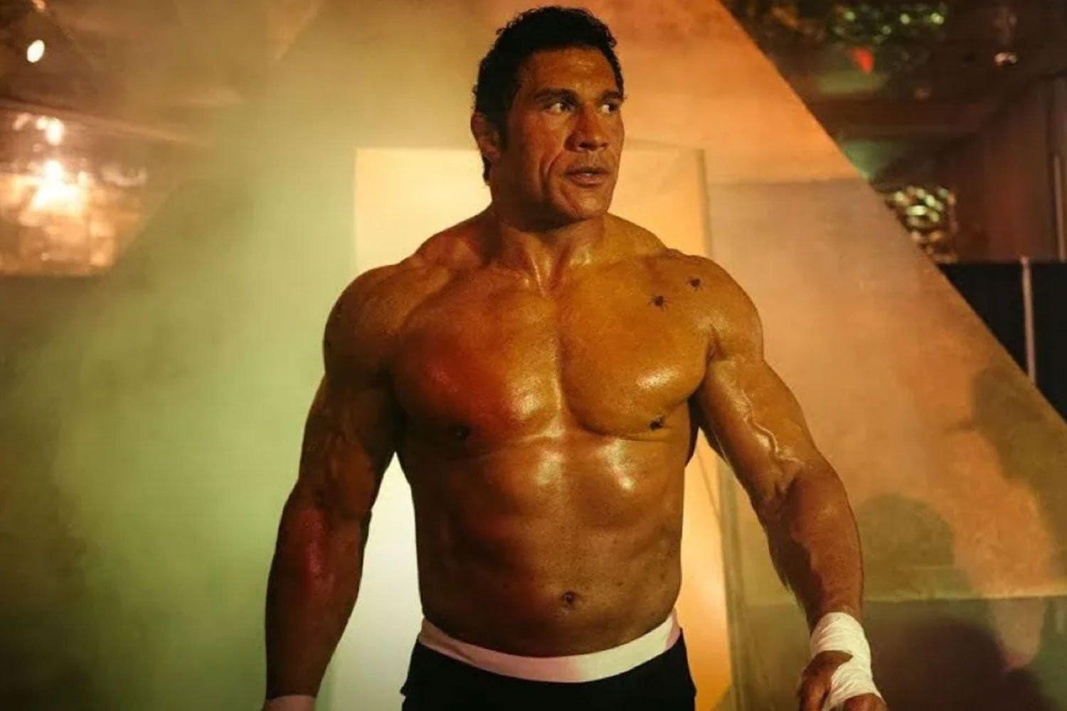 Dwayne Johnson as UFC champion Mark Kerr in Benny Safdie’s The Smashing Machine, mid-fight under harsh ring lights.